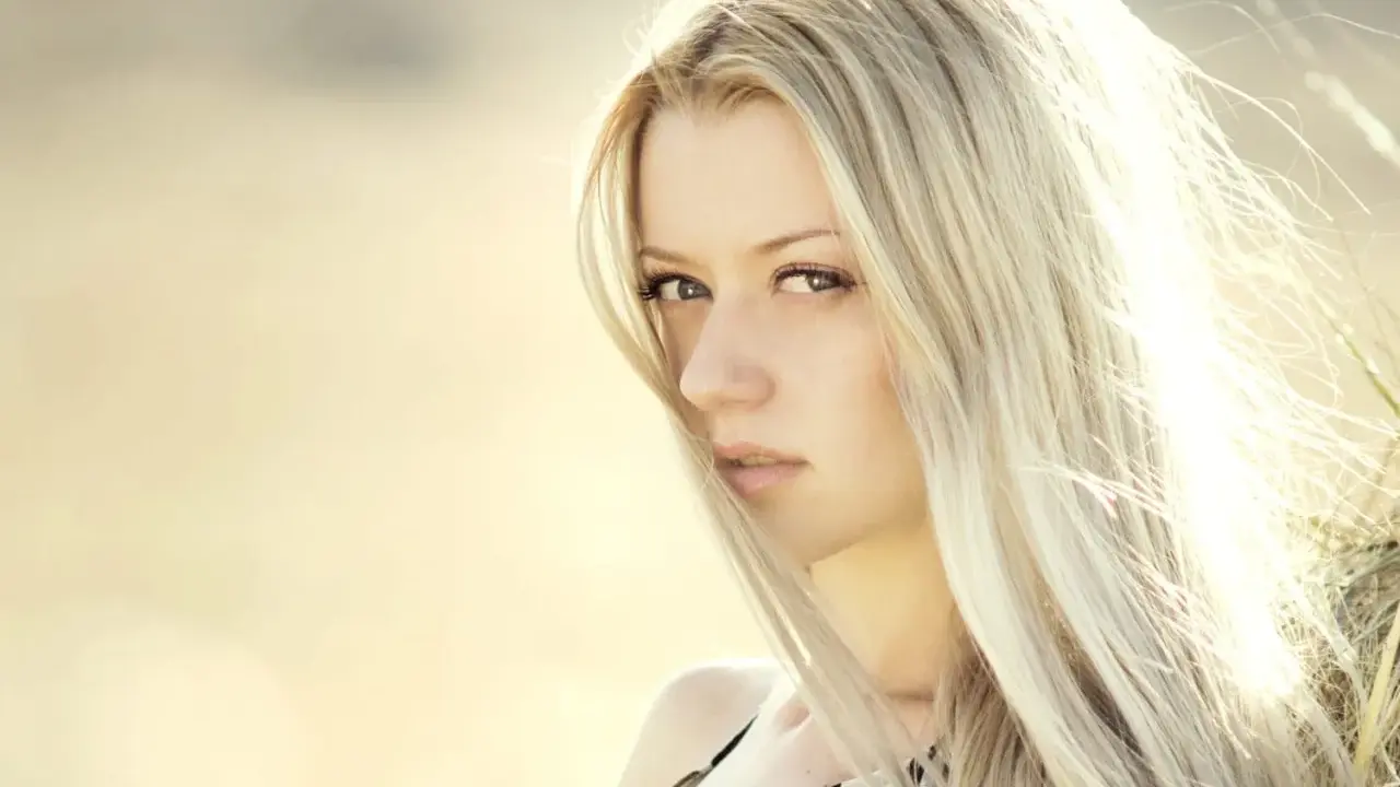 Portrait d'une femme aux cheveux blond platine, le vent caressant son visage.