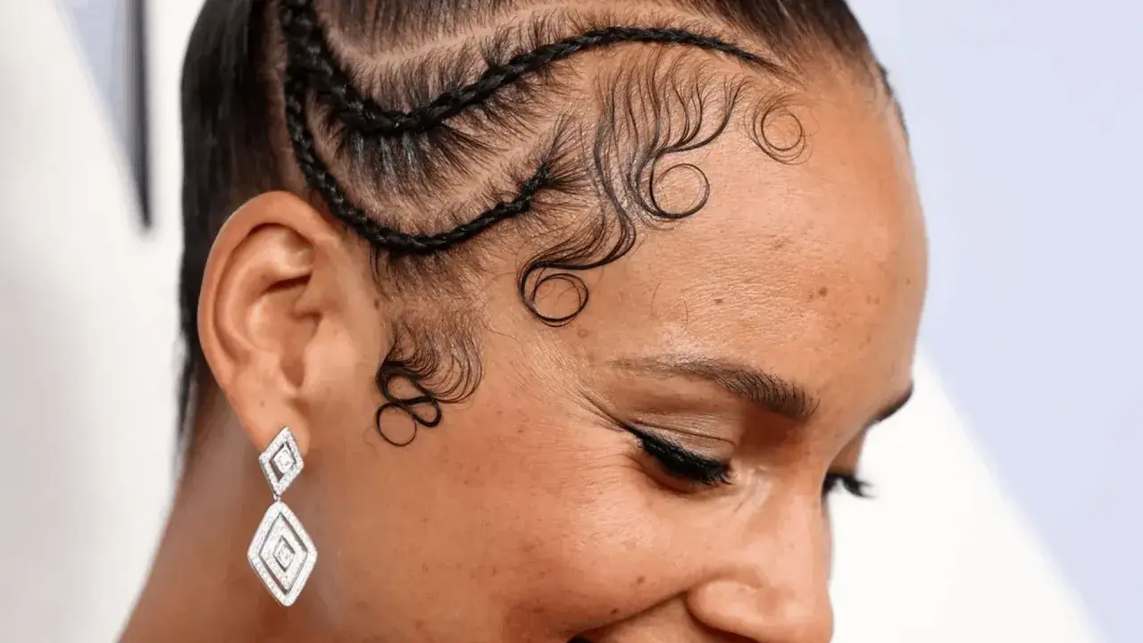 Coiffure avec des tresses et des boucles élégantes sur la hairline cheveux bouclés. Boucles artistiques encadrant le visage.