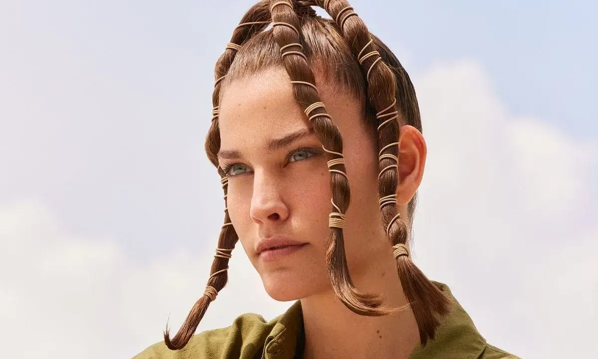 Coiffure d'été audacieuse avec des mèches torsadées et enroulées de fils dorés, rappelant des tentacules aériens sous un ciel bleu.
