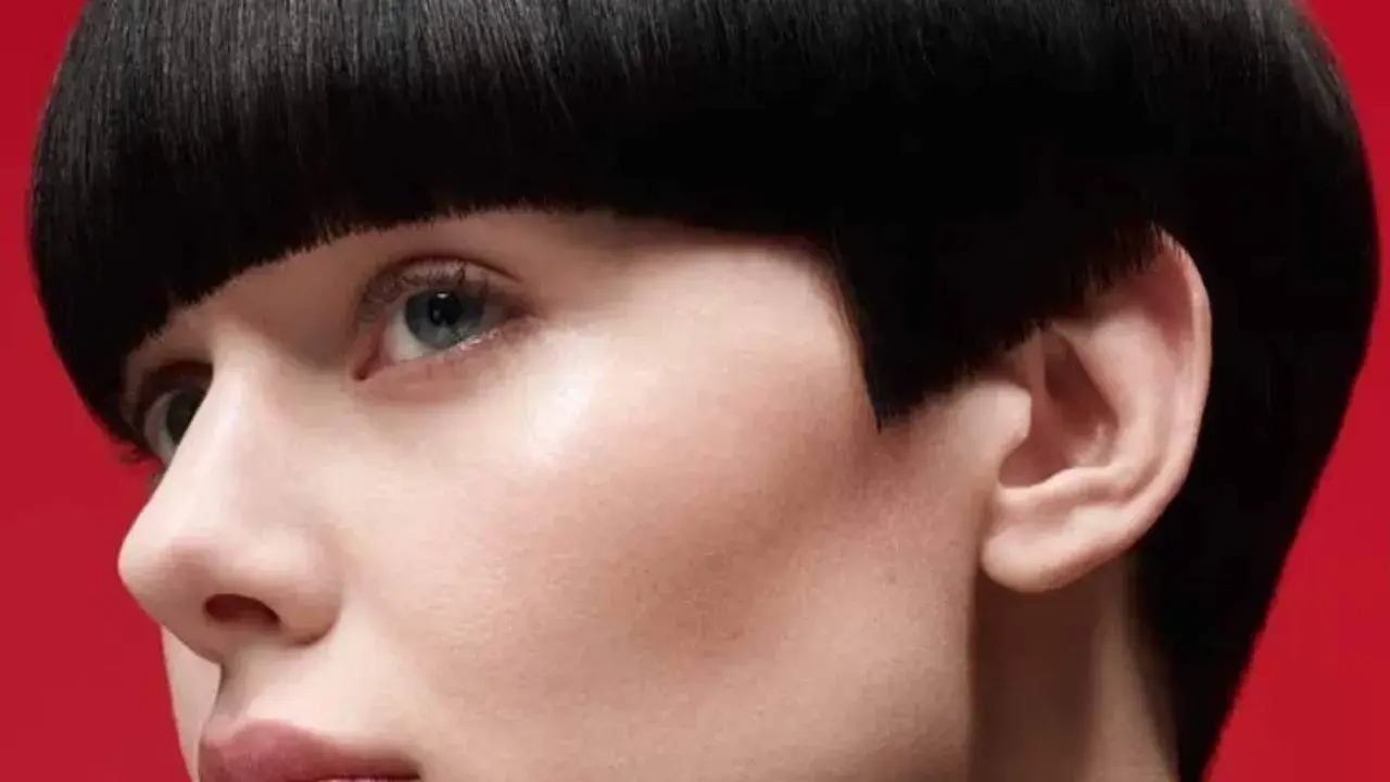 Un visage féminin avec une coupe de cheveux audacieuse, un carré court et arrondi. Ce nom de coupe de cheveux femme met en valeur le regard.