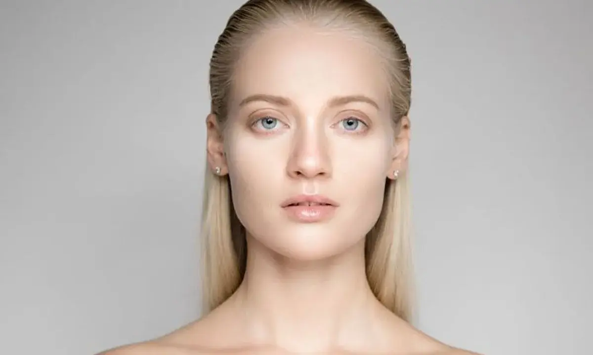 Portrait d'une jeune femme aux yeux bleus et aux cheveux gominés, mise en valeur par une lumière douce.