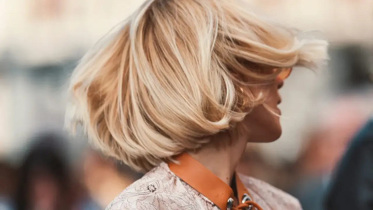 Cheveux blonds balayés par le vent, une coiffure bohème en carré, avec des mèches ondulées qui encadrent le visage.