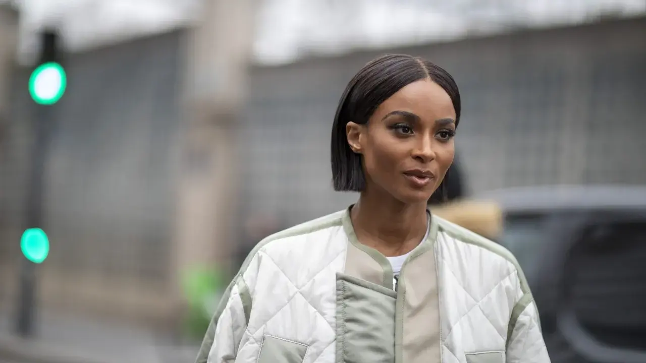 Une femme au regard intense arbore une coupe carré long impeccable, vêtue d'une veste matelassée tendance.
