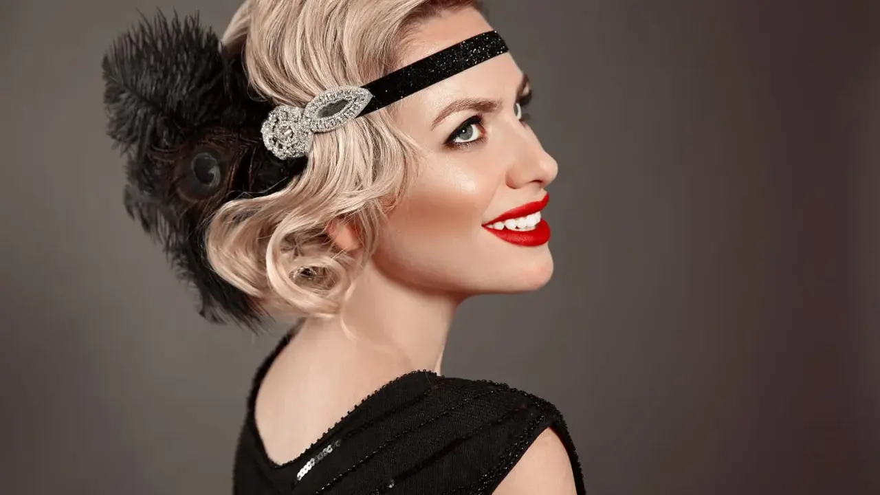 Coiffure année 20 cheveux long, avec bandeau orné de plumes et de strass. Une touche glamour pour une soirée chic.