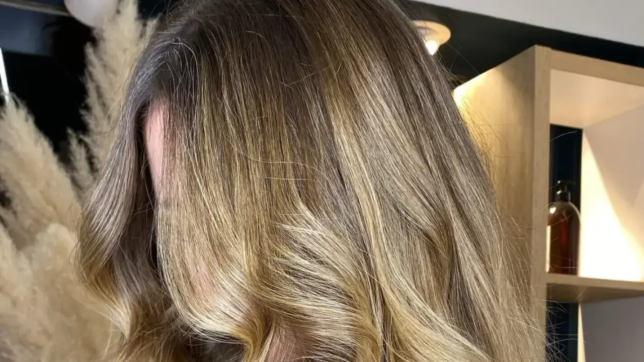 Chevelure longue et ondulée avec un magnifique effet soleil, des reflets blonds dorés qui illuminent la masse.
