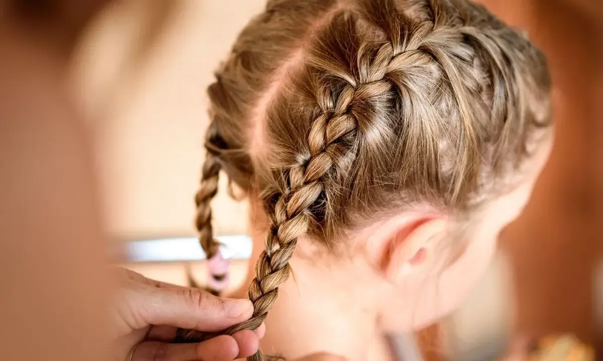 Une coiffure petite fille tresse facile, avec deux nattes bien serrées sur le dessus de la tête.