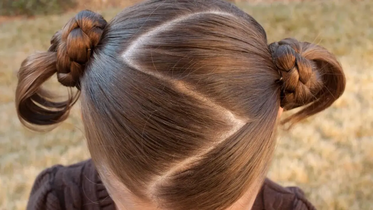 Cheveux bruns tressés en deux couettes rondes, séparés par une raie zig zag.