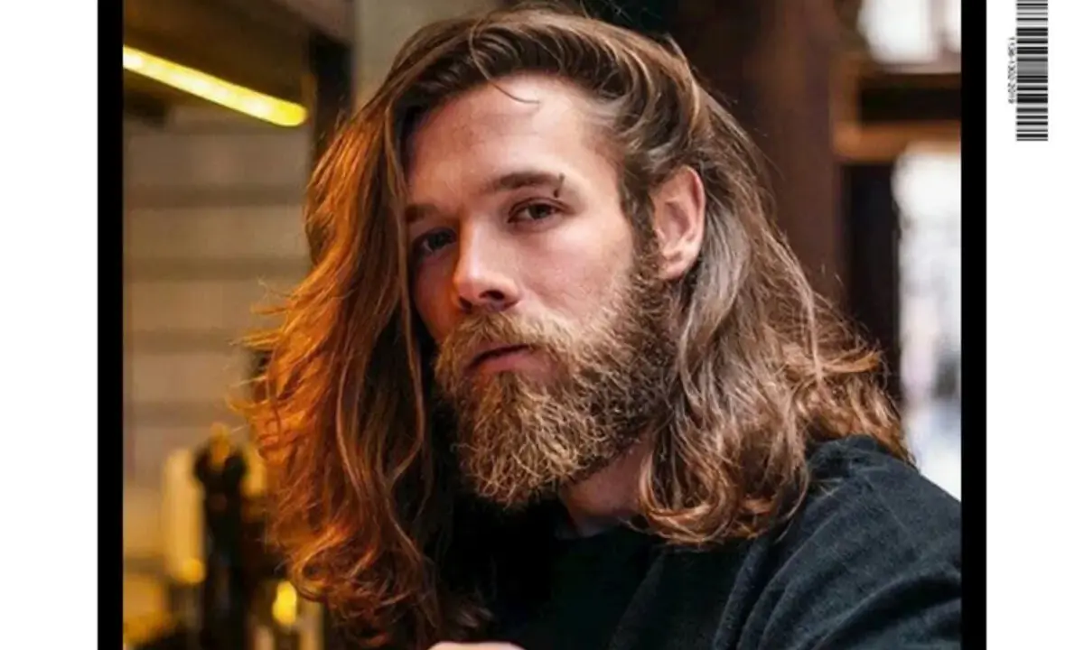 Un homme avec une barbe et de longs cheveux ondulés, parfait pour un projet cheveux long homme.