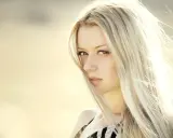 Portrait d'une femme aux cheveux blond platine, le vent caressant son visage.
