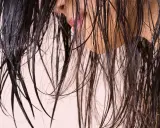 Cheveux sombres et humides tombant en cascade, révélant un aperçu d'une bouche rose et d'une peau claire.