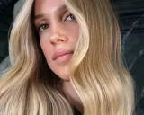 Une femme aux yeux verts et aux lèvres pulpeuses arbore une chevelure ondulée d'une magnifique teinte de blond.
