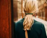 Coiffure avec barrette ornée de pierres vertes, retenant une queue de cheval blonde.