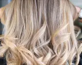 Chevelure ondulée d'un blond polaire lumineux, aux reflets subtils et naturels.