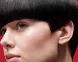 Un visage féminin avec une coupe de cheveux audacieuse, un carré court et arrondi. Ce nom de coupe de cheveux femme met en valeur le regard.