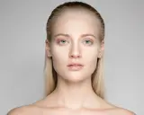 Portrait d'une jeune femme aux yeux bleus et aux cheveux gominés, mise en valeur par une lumière douce.