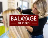 Une coiffeuse applique un balayage blond sur les cheveux d'une femme.