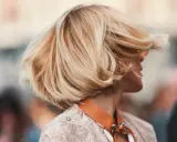 Cheveux blonds balayés par le vent, une coiffure bohème en carré, avec des mèches ondulées qui encadrent le visage.