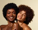 Deux femmes souriantes, l'une avec des cheveux crépus 4c noirs, l'autre avec des boucles rousses.