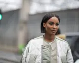 Une femme au regard intense arbore une coupe carré long impeccable, vêtue d'une veste matelassée tendance.