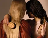 Deux femmes se serrent, l'une brosse les cheveux blonds de l'autre avec une brosse en bois.