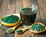 Spiruline en poudre, comprimés et boisson verte sur fond de bois. Découvrez les bienfaits spiruline cheveux pour une chevelure éclatante.