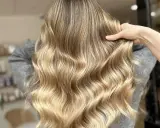 Une chevelure ondulée aux reflets dorés, un blond subtil qui joue avec la lumière.