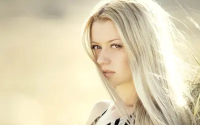 Portrait d'une femme aux cheveux blond platine, le vent caressant son visage.