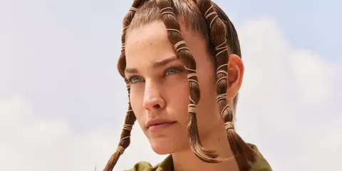 Coiffure d'été audacieuse avec des mèches torsadées et enroulées de fils dorés, rappelant des tentacules aériens sous un ciel bleu.