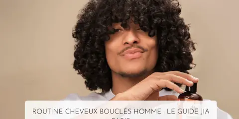 Un homme aux cheveux bouclés tient un flacon de shampoing, parfait pour l'hydratation cheveux bouclés.