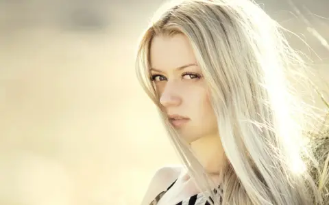 Portrait d'une femme aux cheveux blond platine, le vent caressant son visage.