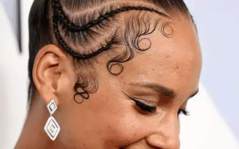 Coiffure avec des tresses et des boucles élégantes sur la hairline cheveux bouclés. Boucles artistiques encadrant le visage.