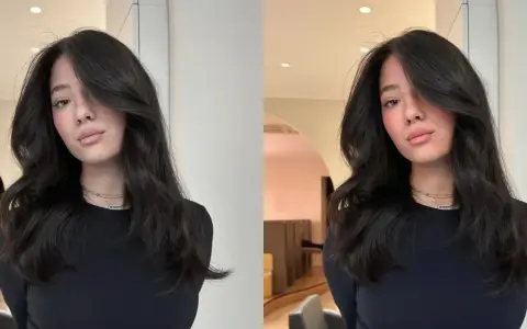 Une jeune femme aux cheveux bruns et brillants, pose avec un sourire subtil. Elle porte un col roulé noir et des colliers fins. On se demande combien de temps dure un gloss cheveux pour obtenir un tel éclat.