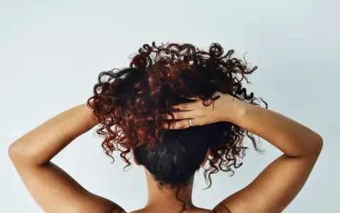 Cheveux bouclés, comme après une baignade dans l'eau salée, sont coiffés par des mains sur fond blanc.