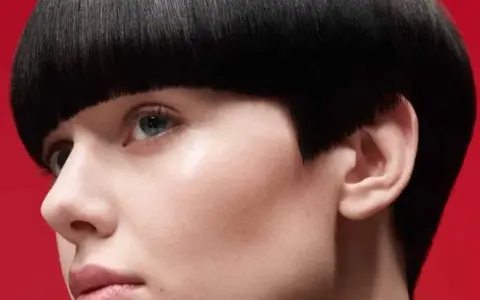 Un visage féminin avec une coupe de cheveux audacieuse, un carré court et arrondi. Ce nom de coupe de cheveux femme met en valeur le regard.