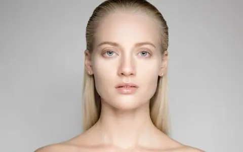 Portrait d'une jeune femme aux yeux bleus et aux cheveux gominés, mise en valeur par une lumière douce.