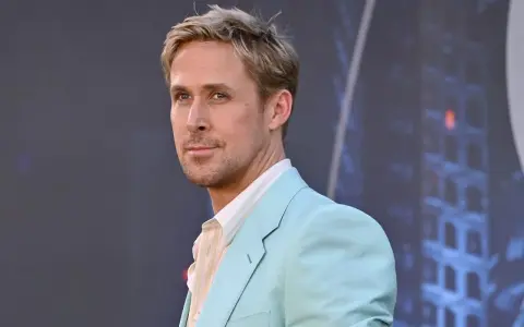 Ryan Gosling, avec une coupe homme cheveux fins, porte un costume bleu pastel et une chemise à rayures.