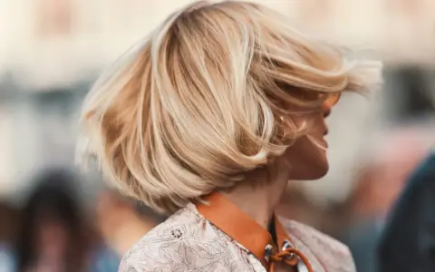 Cheveux blonds balayés par le vent, une coiffure bohème en carré, avec des mèches ondulées qui encadrent le visage.