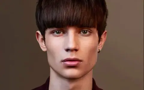 Un jeune homme au regard intense arbore une coupe au bol homme audacieuse, encadrant son visage aux traits fins.