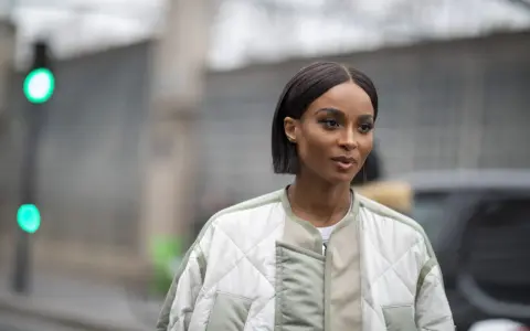 Une femme au regard intense arbore une coupe carré long impeccable, vêtue d'une veste matelassée tendance.