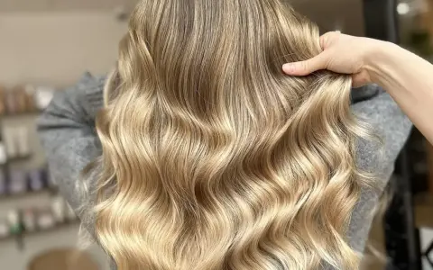 Une chevelure ondulée aux reflets dorés, un blond subtil qui joue avec la lumière.