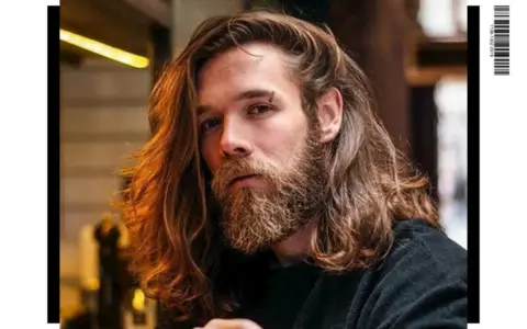 Un homme avec une barbe et de longs cheveux ondulés, parfait pour un projet cheveux long homme.