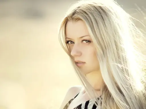 Portrait d'une femme aux cheveux blond platine, le vent caressant son visage.