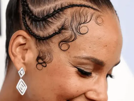 Coiffure avec des tresses et des boucles élégantes sur la hairline cheveux bouclés. Boucles artistiques encadrant le visage.