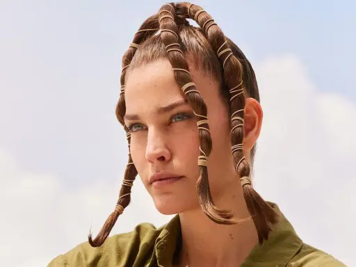 Coiffure d'été audacieuse avec des mèches torsadées et enroulées de fils dorés, rappelant des tentacules aériens sous un ciel bleu.