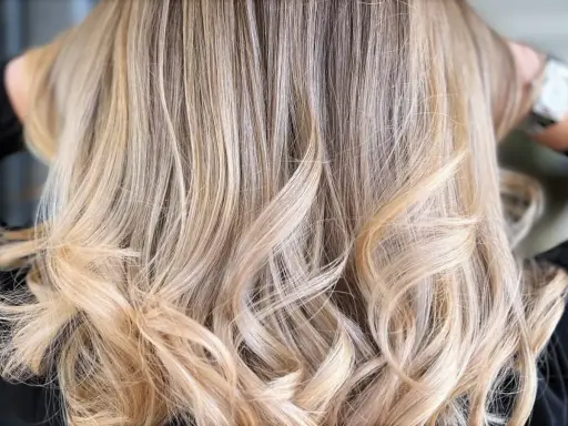 Chevelure ondulée d'un blond polaire lumineux, aux reflets subtils et naturels.
