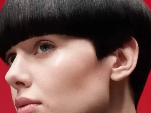 Un visage féminin avec une coupe de cheveux audacieuse, un carré court et arrondi. Ce nom de coupe de cheveux femme met en valeur le regard.