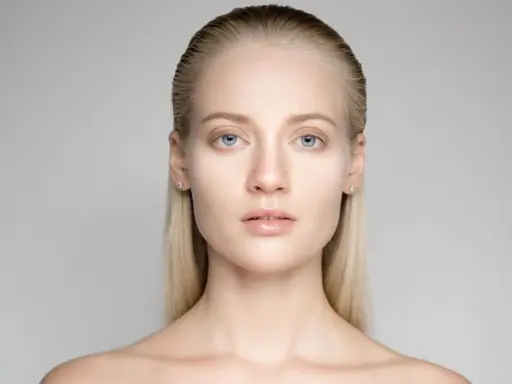 Portrait d'une jeune femme aux yeux bleus et aux cheveux gominés, mise en valeur par une lumière douce.