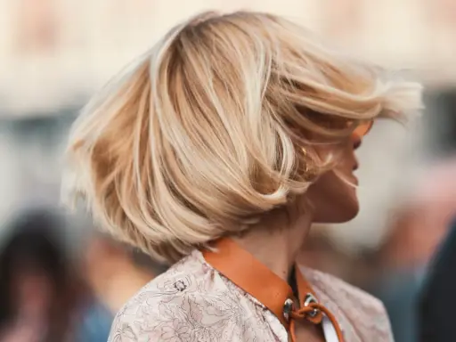 Cheveux blonds balayés par le vent, une coiffure bohème en carré, avec des mèches ondulées qui encadrent le visage.