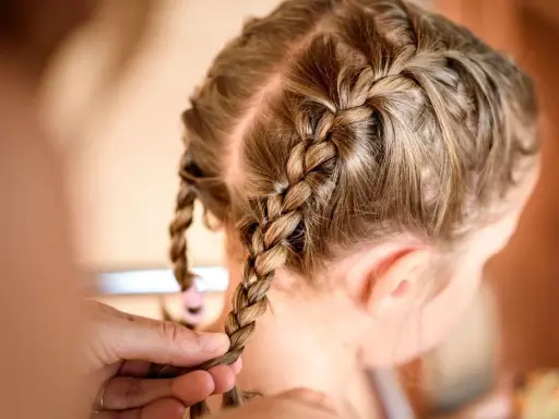 Une coiffure petite fille tresse facile, avec deux nattes bien serrées sur le dessus de la tête.