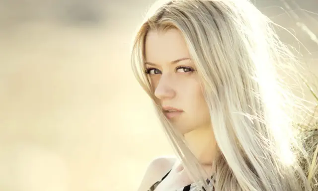 Portrait d'une femme aux cheveux blond platine, le vent caressant son visage.